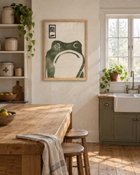 Lifestyle: kitchen — White clapboard Maine farmhouse, circa 1890, with a renovated but character-retaining kitchen — plaster walls, wide-plank pine floors, and a deep farmhouse sink beneath a multi-pane window.